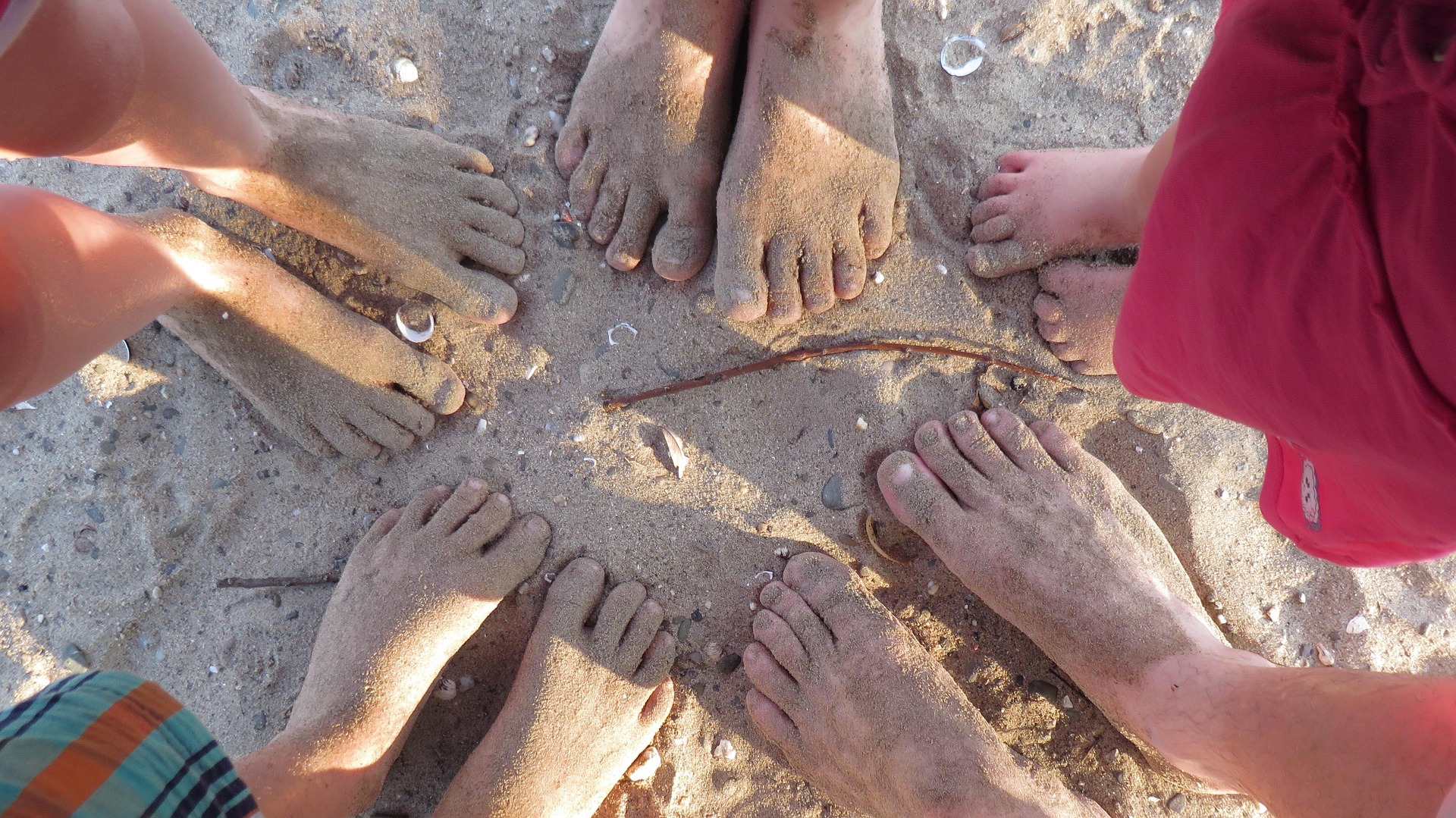 A group of sandy bare feet on the beach